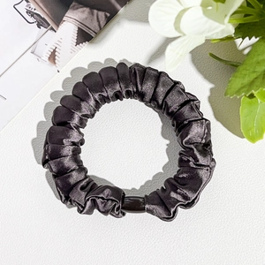 Detail view of premium black silk satin scrunchie with elegant pleated texture and resin bead
