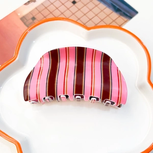 Détail d'une pince à cheveux à rayures rouges et blanches sur une assiette en porcelaine