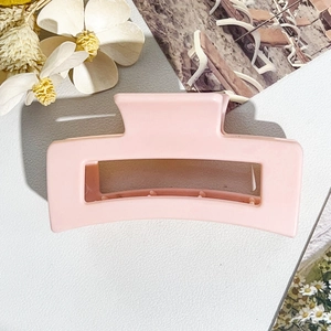 Detail of pink matte rectangular hair claw clip with non-slip teeth on a white surface