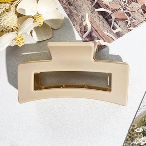 Close-up of a matte beige square hollow claw clip on a white leather texture