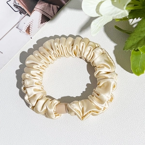 Detailed macro view of champagne silk scrunchie with soft pleats and elegant round fastener