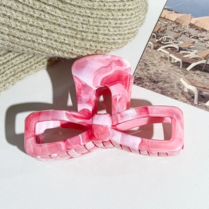 Detailed top view of a pink marble pattern bow hair claw clip on a soft knit background
