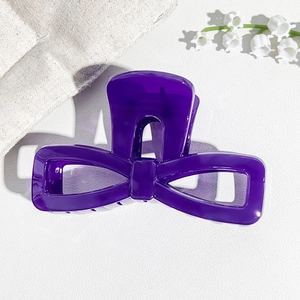 Detail of a large purple UV painted bow hair claw clip with a glossy hollow resin finish
