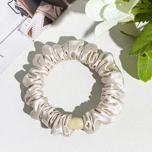Detail of champagne silk scrunchie with pearl beads and satin pleated texture
