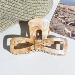 Detail view of marble patterned bow hair claw clip with cream acrylic texture