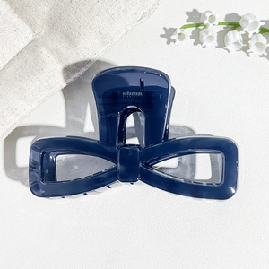 Detail of a navy blue bow hair claw clip with a glossy finish and hollow design