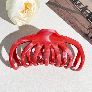 Red marble pattern octopus hair claw clip shown on an elegant aesthetic background