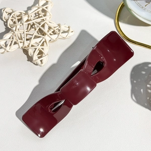 Dettaglio ravvicinato di un fermaglio per capelli a fiocco bordeaux con finitura lucida