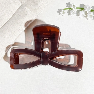 Detailed top view of a tortoise brown acrylic bow hair claw clip with spring detail