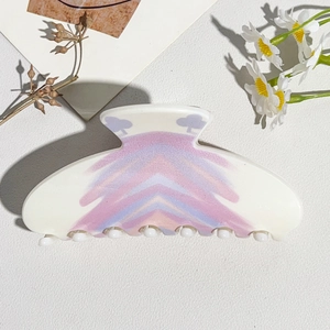 Detail view of flower hair claw clip with colorful wavy patterns on textured background