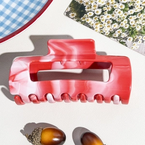 Detail view of large marble texture shark clip hair accessory on decorative background