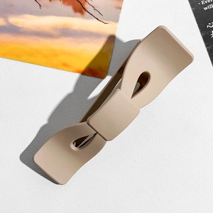 Grosse pince à cheveux beige mat en forme de nœud sur fond de texture cuir blanc