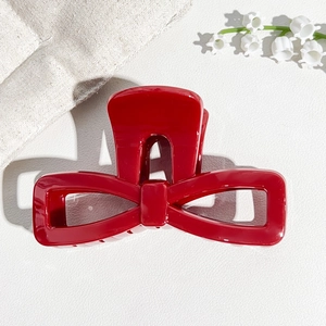 Detail of red hollow bow shark hair claw clip made of high gloss resin on white surface
