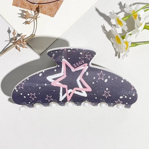 Detail of greyish-purple hair claw clip with star patterns and Star text on white leather