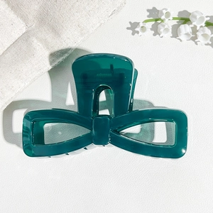Detailed close-up of dark green bow-shaped hair claw clip with glossy resin finish