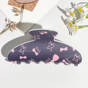 Close-up of a matte dark grey hair claw clip featuring pink butterfly and bow patterns