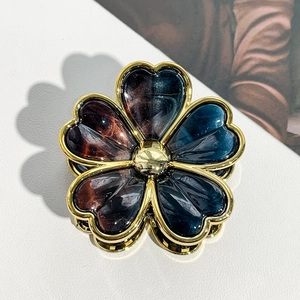 Detailed macro view of a gold-edged floral hair claw with marbled enamel petals