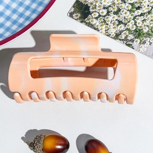 Detail of soft silicone shark hair clip with cream orange marble texture for women