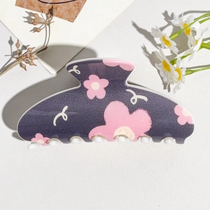 Detail view of purple matte hair claw clip with pink floral patterns on a white background