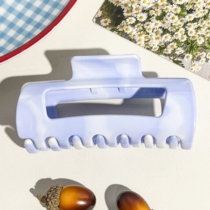 Detail of soft purple marble hair claw clip with cutout design on chic white background