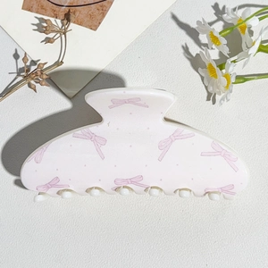 Close-up of semi-round hair claw with pink bow pattern and smooth acrylic texture