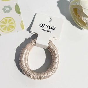 Détail de la texture satinée plissée couleur champagne et du tissu du chouchou cheveu