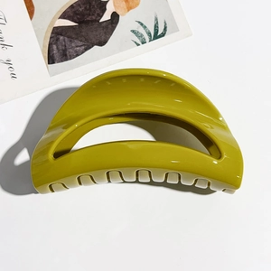 Close-up of olive green glossy claw clip showing hollow semi-circular design and teeth