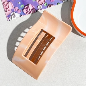 Detail of square hollow hair claw clip with cream marble texture on a white background