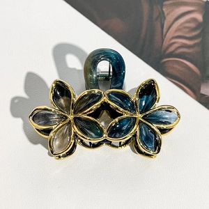 Close-up of dual flower hair claw clip with gradient petals and gold metal edging details