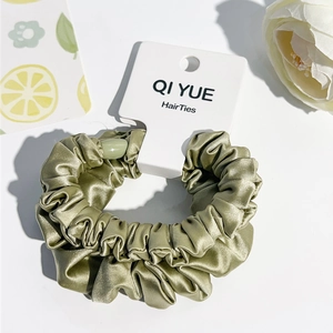 Vue détaillée du chouchou en satin vert olive avec étiquette et décor floral élégant