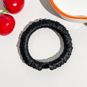 Detail of black seamless ice silk hair scrunchie with satin texture and plastic ring