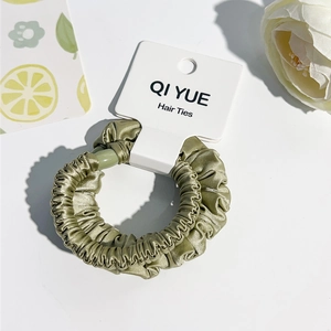 Vue détaillée du chouchou en satin vert olive avec texture à volants sur la carte