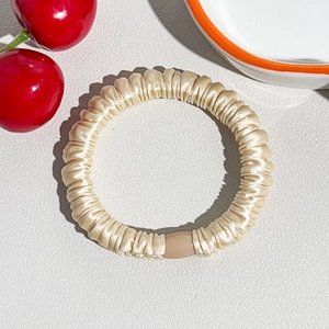 Detailed macro view of champagne silk scrunchie with smooth pleated texture and durable buckle