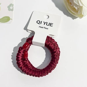 Détail du chouchou en satin bordeaux avec perles rouges sur carte de présentation blanche
