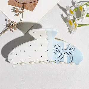 Detail of blue bow and black heart prints on a sweet cream acetate square hair claw clip
