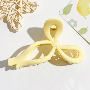 Detailed top view of a cream yellow moon-shaped claw clip with a strong gold spring