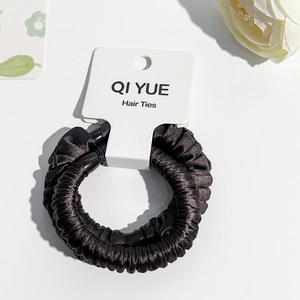 Vue détaillée de chouchous en satin noir avec texture plissée sur carte blanche
