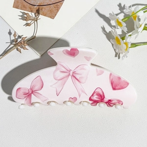 Detail of pink half-round hair claw clip with sweet bow and heart pattern prints