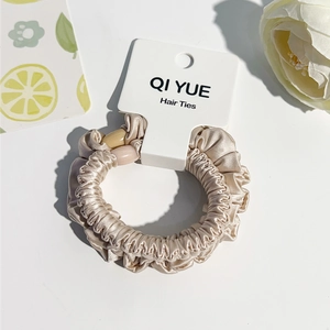 Détail du chouchou en satin champagne avec perles et emballage de marque
