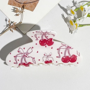 Detail of a white hair claw clip with cherry and bow prints for Valentine's hairstyles