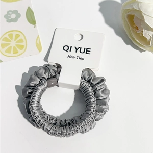 Vue détaillée du chouchou en satin gris avec texture plissée sur son emballage