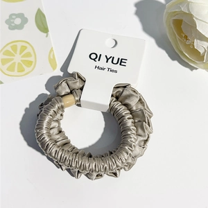 Détail du chouchou en satin plissé champagne avec perle et étiquette de marque QI YUE