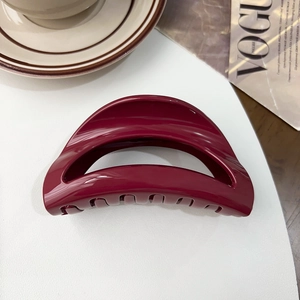 Close-up of a burgundy square hair claw clip on a minimalist lifestyle magazine background