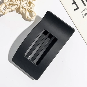 Detail of a matte black square hollow hair claw clip on a white decorative background