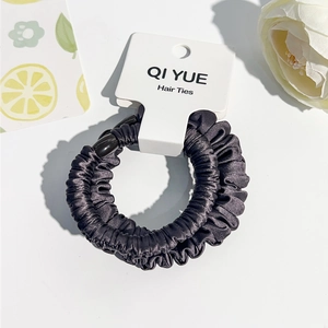 Vue détaillée du chouchou en satin gris plissé présenté sur un emballage blanc