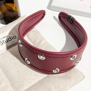 Close-up of burgundy PU leather headband featuring silver metal eyelets and soft inner lining