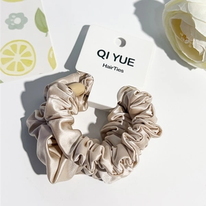 Détail d'un chouchou en satin doré champagne avec texture de soie lisse et volants