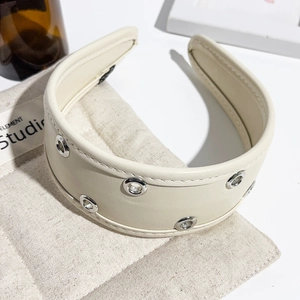 Close-up of beige PU leather headband featuring silver metal eyelets and fine stitching details