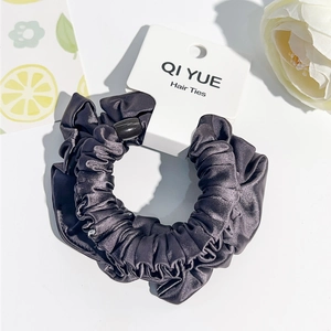 Détail du chouchou en satin gris foncé avec perle décorative sur carte de présentation