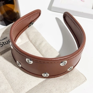 Detail view of the deep brown leather headband with silver metal eyelets and stitching
